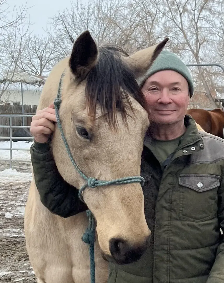 A man standing next to a horse in the snow.